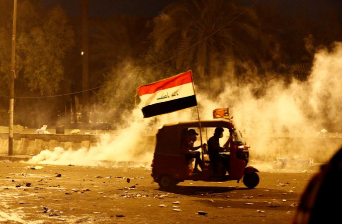 Một chiếc tuk-tuk đang cố thoát khỏi hơi cay từ lực lượng an ninh trong một cuộc biểu tình ở Baghdad, Iraq ngày 26/10/ Ảnh: Thaier Al-Sudani