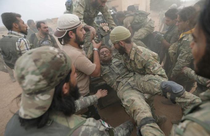 Một người lính quân nổi dậy Syria đang hỗ trợ đồng đội bị thương thị trấn biên giới Tal Abyad, Syria, ngày 24/10. / Ảnh: Khalil Ashawi