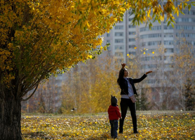 Một người phụ nữ đang ném tung những chiếc lá vàng trong công viên ở Nur-Sultan, Kazakhstan/Pavel Mikheyev