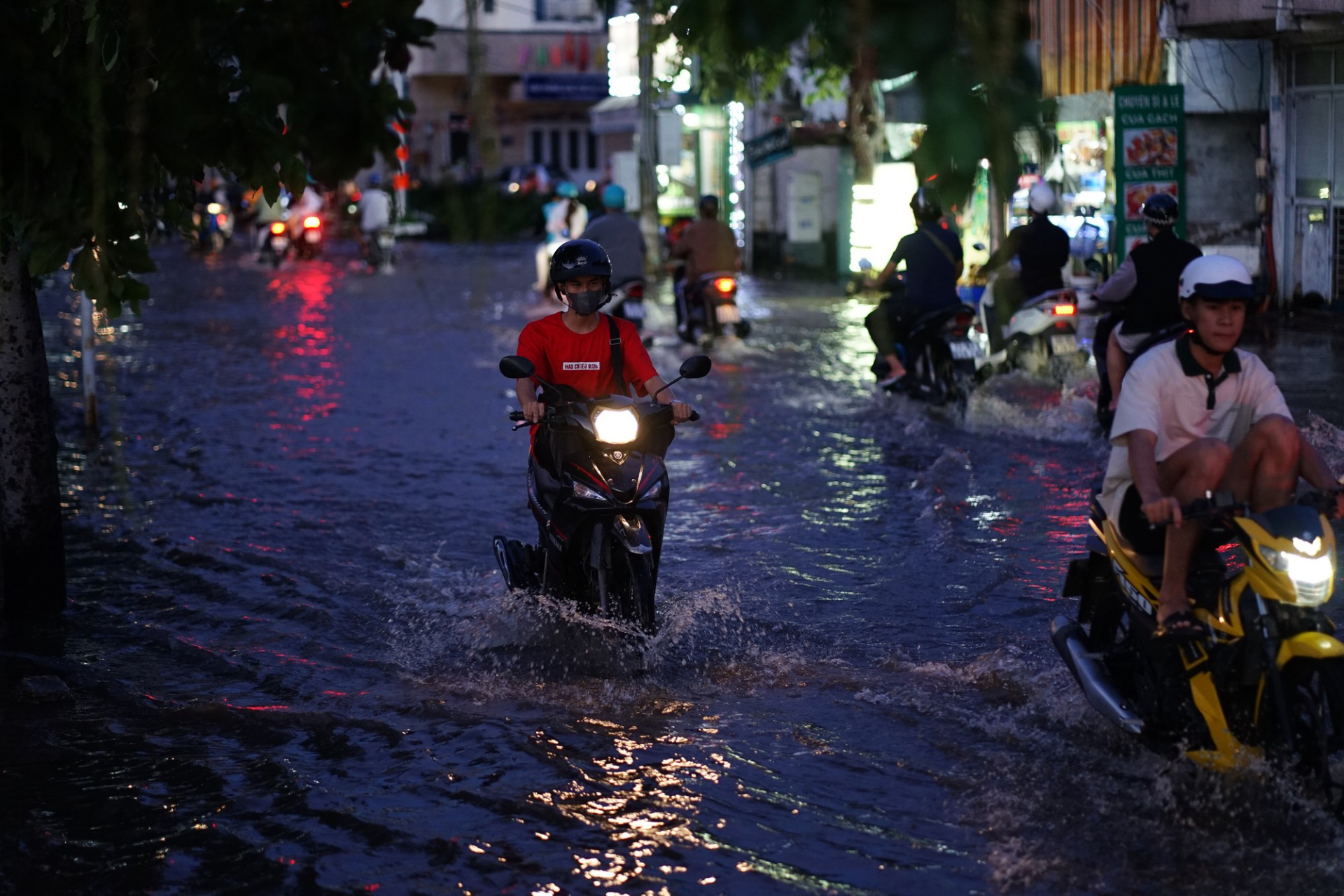 Nước triều cường che khuất các ổ gà, ổ voi trên mặt đường, tiềm ẩn nguy cơ khiến người đi xe máy gặp tai nạn (Ảnh: Di Anh)