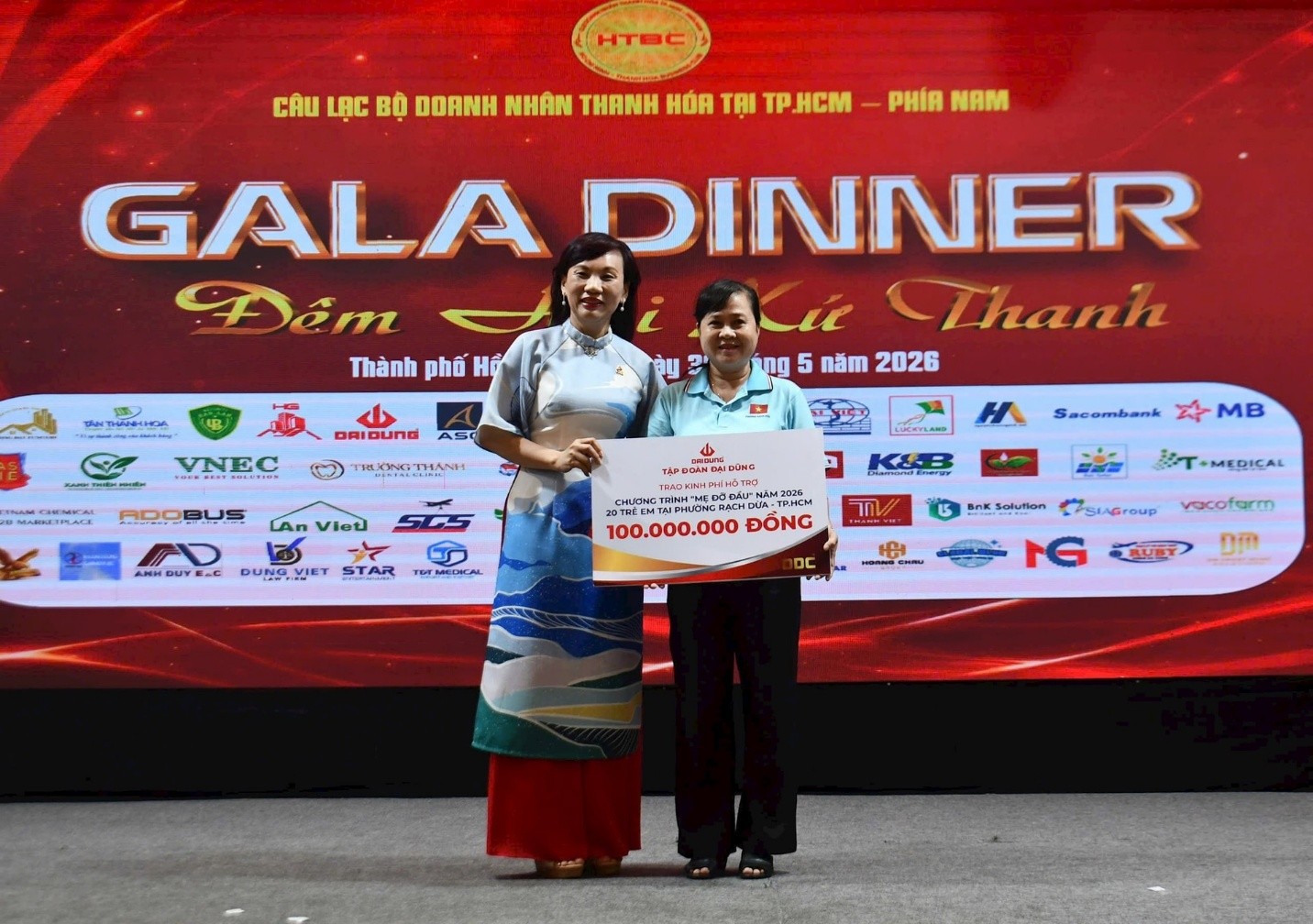 Bà Nguyễn Thị Hồng Liên (bên trái), Thành viên HĐQT, Phó TGĐ Tập đoàn Đại Dũng trao 100 triệu đồng tiền đỡ đầu 20 trẻ mồ côi, trẻ có hoàn cảnh đặc biệt khoá khăn trong năm 2026 cho bà Nguyễn Thị Kim Phượng, Phó Chủ tịch Ủy ban MTTQ Việt Nam phường Rạch Dừa
