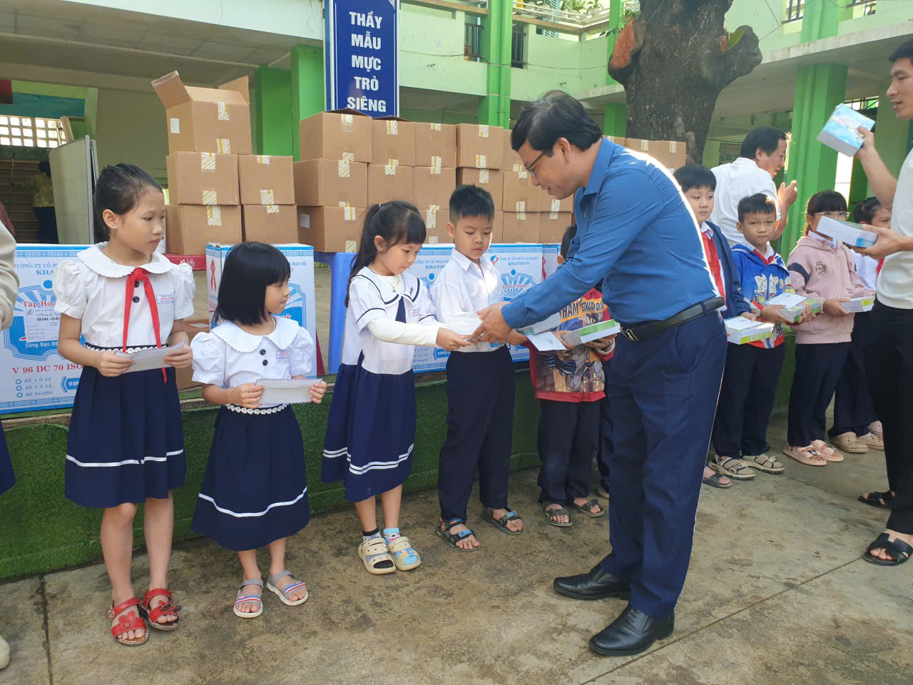 Các con nhận vở và tiền để mua dụng cụ học tập từ các cô, chú Nhà báo trao tặng trong niềm hạnh phúc sau nhiều ngày mưa lũ...