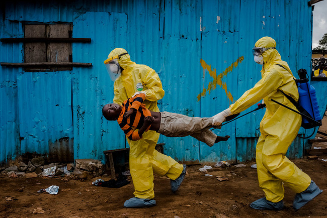  Dịch Ebola bùng phát ở Guinea hồi tháng 3, lan tới các nước láng giềng khác ở Tây Phi như Liberia, Sierra Leone, Nigeria và Senegal. Sau đó, người ta tiếp tục ghi nhận nhiều trường hợp nhiễm Ebola tại Mỹ và các quốc gia châu Âu như Tây Ban Nha, Pháp, Anh, Hà Lan, Đức, Thụy Sĩ, Na Uy. Trong ảnh là cậu bé James Dorbor, 8 tuổi bị nhiễm bệnh đang được các nhân viên y tế đưa đi điều trị Ebola.