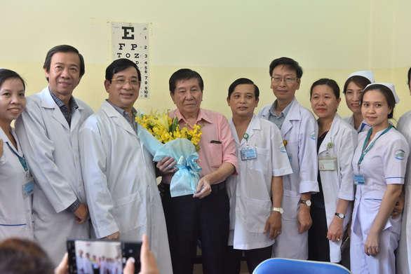 Ông Lương Ngọc Khuê, cục trưởng Cục quản lý Khám chữa bệnh, tặng hoa cho ông Tạ Hoa Kiên khi ông xuất viện.