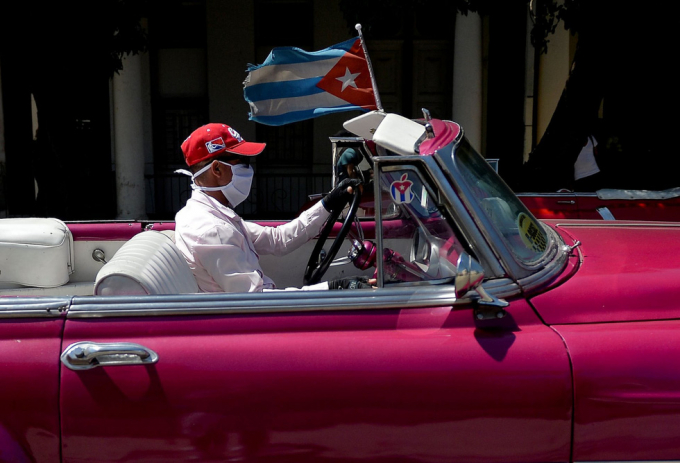   Một tài xế taxi chạy xe mui trần, đeo găng tay và khẩu trang ngừa COVID-19 tại Havana, Cuba - Ảnh: AFP  