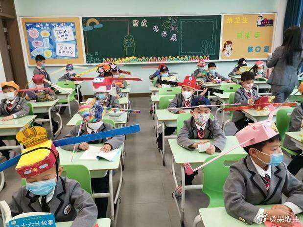   Học sinh một trường tiểu học tại thành phố Hàng Châu, tỉnh Chiết Giang, đội mũ tự chế để đảm bảo giãn cách với các bạn trong lớp vào ngày đầu đi học lại. Ảnh: CGTN  