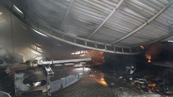 Mái tôn của một xưởng gỗ đổ sập trong đám cháy. 