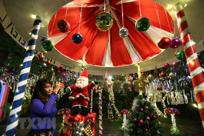   Người dân chụp ảnh bên đồ trang trí chào đón Giáng sinh tại Yangon, Myanmar. (Ảnh: THX/TTXVN)  