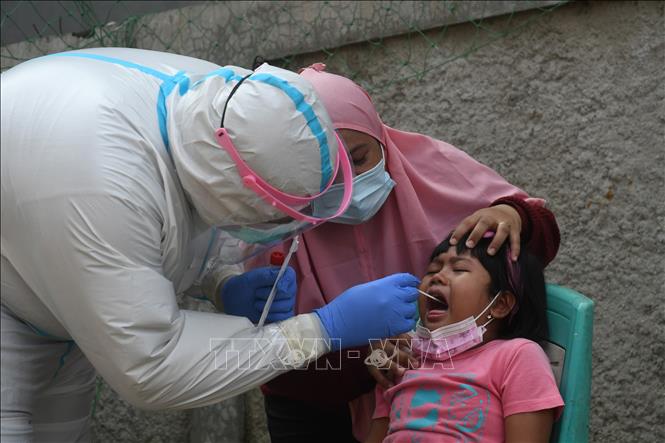 Nhân viên y tế lấy mẫu xét nghiệm COVID-19 cho trẻ em tại Jakarta, Indonesia, ngày 20/5/2021. Ảnh: THX/TTXVN