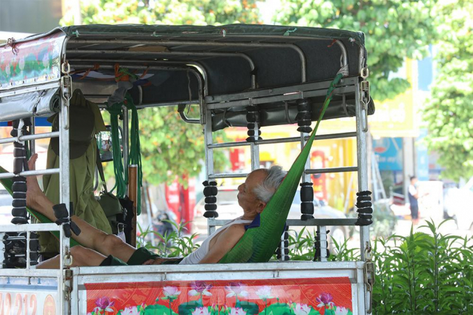           Một bác lái xe mắc võng nghỉ trưa dưới gầm đường vành đai 3 trên đường Nguyễn Xiển          
