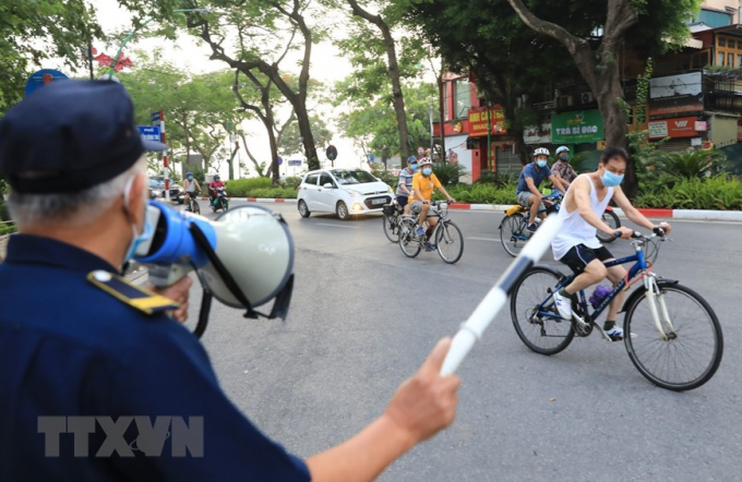 Lực lượng dân phòng liên tục gọi loa nhắc nhở người dân không đạp xe tập thể dục tại đường Thanh Niên (Ảnh chụp 6h sáng 19/7). (Ảnh: Thành Đạt/TTXVN)