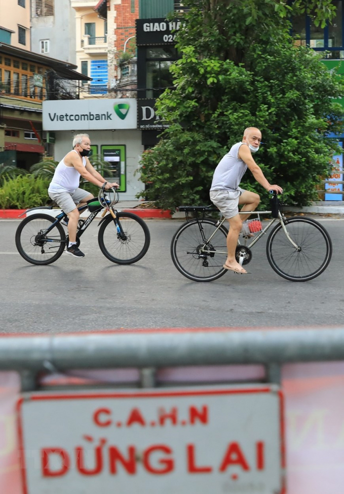 Dù có biển cấm và rào chắn người dân vẫn đạp xe tập thể dục trên đường Thanh Niên dọc hồ Tây (Ảnh chụp 5h30 sáng 19/7). (Ảnh: Thành Đạt/TTXVN)