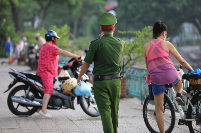 Lực lượng công an phường Thụy Khuê nhắc nhở người dân không tập thể dục tại đường Thanh Niên (Ảnh chụp 6h sáng 19/7). (Ảnh: Thành Đạt/TTXVN)