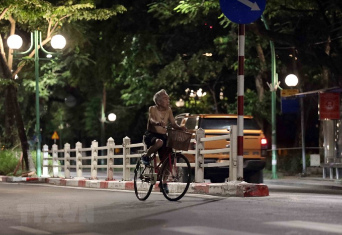 Một người dân đạp xe, không đeo khẩu trang tập thể dục lúc 4h5 sáng 26/7 trên đường Thanh Niên. (Ảnh: Nhật Anh/TTXVN)