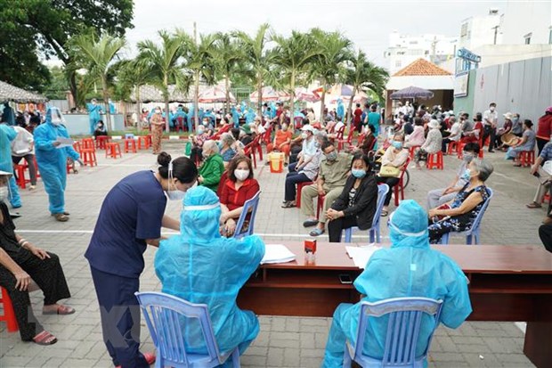   Nhân viên y tế hỗ trợ người dân tra cứu thông tin trước khi thực hiện tiêm chủng tại điểm tiêm UBND phường 9 (quận Gò Vấp, Thành phố Hồ Chí Minh). (Ảnh: Thu Hương/TTXVN)  