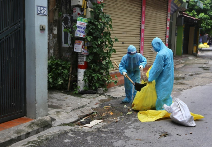 Công nhân môi trường thu gom rác tại các ngõ, ngách khu phong tỏa phường Giáp Bát, góp phần phòng, chống COVID-19. (Ảnh: Hoàng Hiếu/TTXVN)