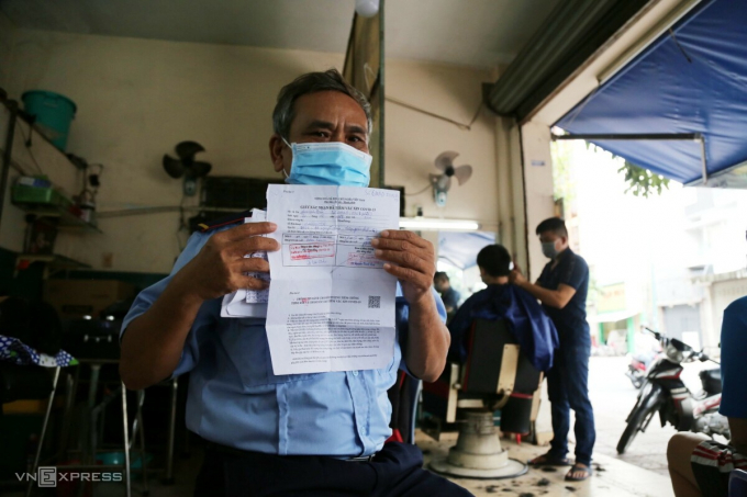   Ông Phan Xuân Đàm (53 tuổi) mang theo giấy chứng nhận tiêm 2 mũi vaccine và chờ gần hai giờ để cắt tóc. 