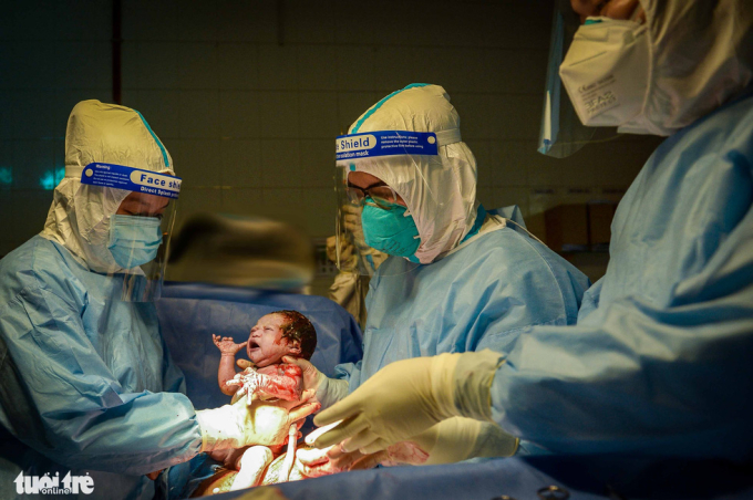   Khoảnh khắc các bác sĩ Bệnh viện Hùng Vương (TP.HCM) phẫu thuật lấy em bé khỏi bụng mẹ thành công, mẹ của bé là một bệnh nhân nhiễm COVID-19, sau ca phẫu thuật, sức khỏe của cả hai mẹ con đều ổn định - Ảnh: TỰ TRUNG  