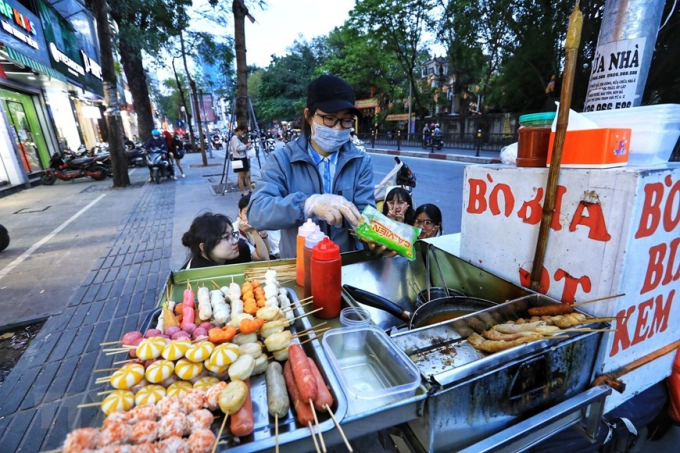 Một xe bán đồ ăn trên vỉa hè phố Chùa Bộc thu hút đông thực khách là trẻ nhỏ. (Ảnh: Tuấn Anh/TTXVN)