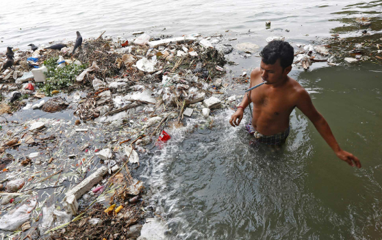 Một người đàn ông đánh răng trong làn nước ô nhiễm của sông Hằng ở Kolkata, Ấn Độ. Ảnh: REUTERS / Rupak De Chowdhuri