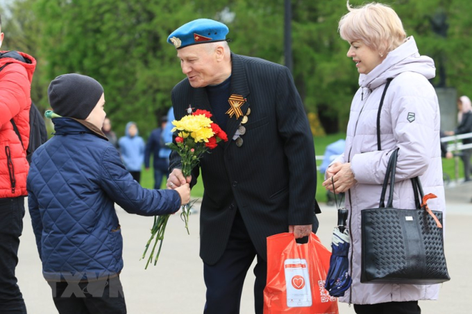 Người cựu chiến binh của Binh chủng đặc nhiệm đổ bộ đường không đón nhận bông hoa tươi thắm từ một cháu nhỏ không quen biết ở trong công viên Gorky. (Ảnh: Trần Hiếu/TXVN)