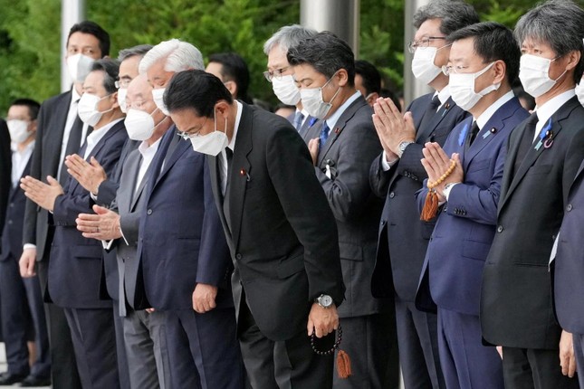           Thủ tướng Kishida Fumio tay cầm tràng hạt cúi đầu tiễn biệt ông Abe. Ảnh: Reuters          