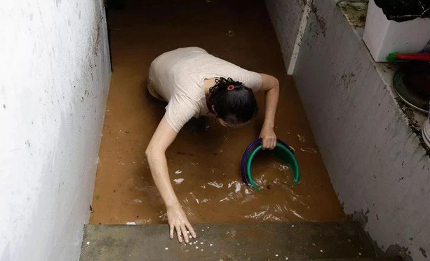   Một người phụ nữ đang cố gắng tát nước mưa ra khỏi nhà.  