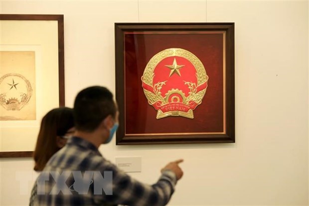 Du khách tham quan triển lãm Phác thảo mẫu Quốc huy Việt Nam của họa sỹ Bùi Trang Chước tại Bảo tàng Mỹ thuật Việt Nam năm 2020. (Ảnh: Thành Đạt/TTXVN)