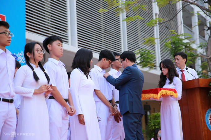   Học sinh lớp 10 trường THPT Phan Châu Trinh (Đà Nẵng) được thầy hiệu trưởng gắn bảng tên lên áo trong lễ khai giảng. Ảnh: Nguyễn Đông  
