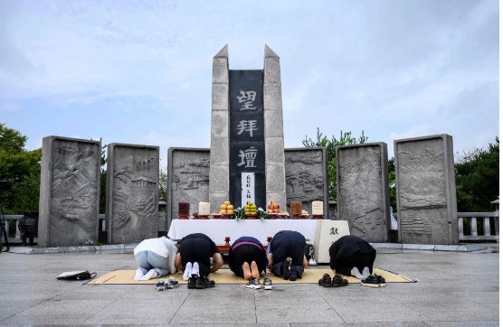 Người dân cúi đầu quỳ lạy một bia tưởng niệm tại Khu vực phi quân sự (DMZ) chia tách Triều Tiên và Hàn Quốc. Ảnh: AFP