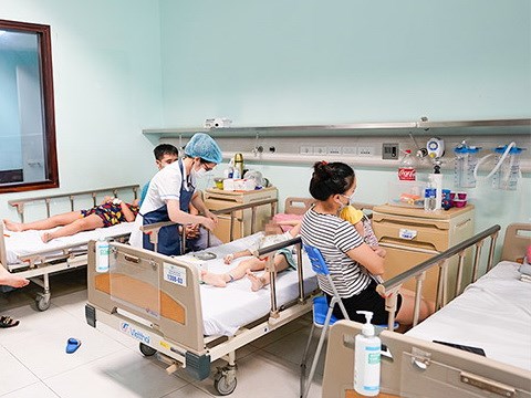   Nhân viên y tế chăm sóc cho trẻ mắc virus Adeno. (Ảnh: PV/Vietnam+)  