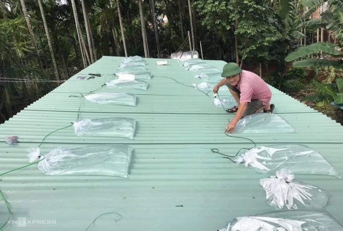 Mái tôn nhà được người dân dùng bao ni lông trắng bơm nước đầy vào để chèn chống bão Noru khỏi tốc mái.