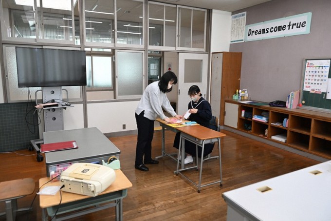   Akino Imanaka (ngồi) trao đổi với giáo viên chủ nhiệm tại trường trung học cơ sở Oteshima ngày 10/3. Ảnh: Mainichi  
