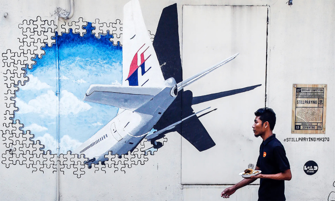   Một người Malaysia đi qua bức tường vẽ tranh tưởng niệm về MH370 tại thủ đô Kuala Lumpur vào năm 2016. Ảnh: AP.  