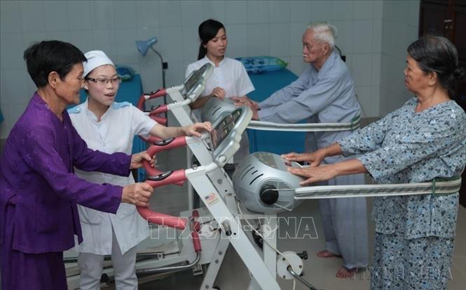Hướng dẫn người có công tập phục hồi chức năng tại Trung tâm chăm sóc người có công với cách mạng tỉnh Bình Định. Ảnh: Anh Tuấn/TTXVN