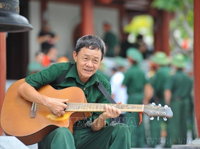 Cựu chiến binh mặt trận Vị Xuyên (Hà Giang) đàn hát cho đồng đội nghe tại Nghĩa trang liệt sĩ quốc gia Vị Xuyên (Hà Giang). Ảnh: Nam Thái/TTXVN