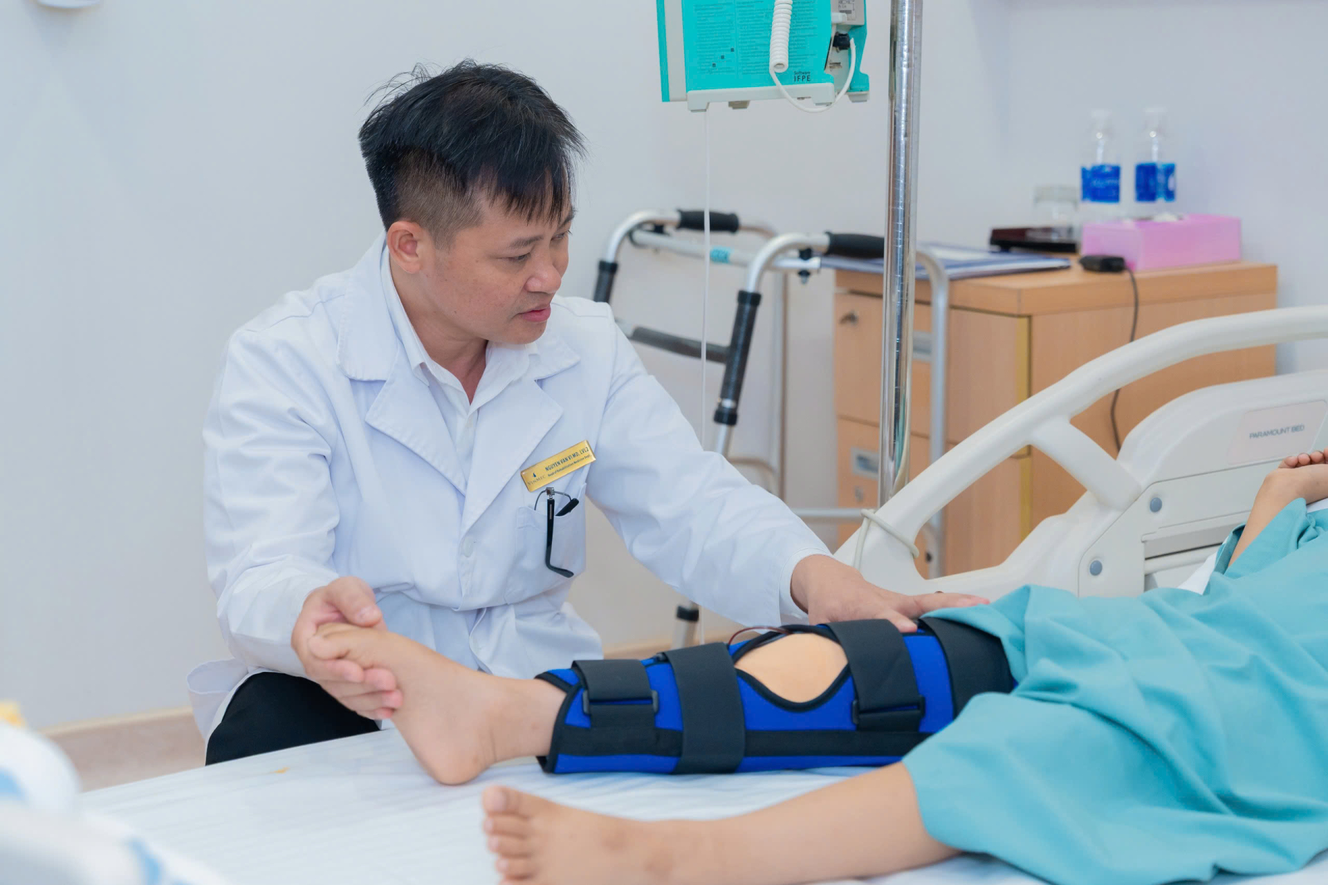  BSCKII Nguyễn Văn Vĩ ân cần hỗ trợ bệnh nhân tập phục hồi chân.