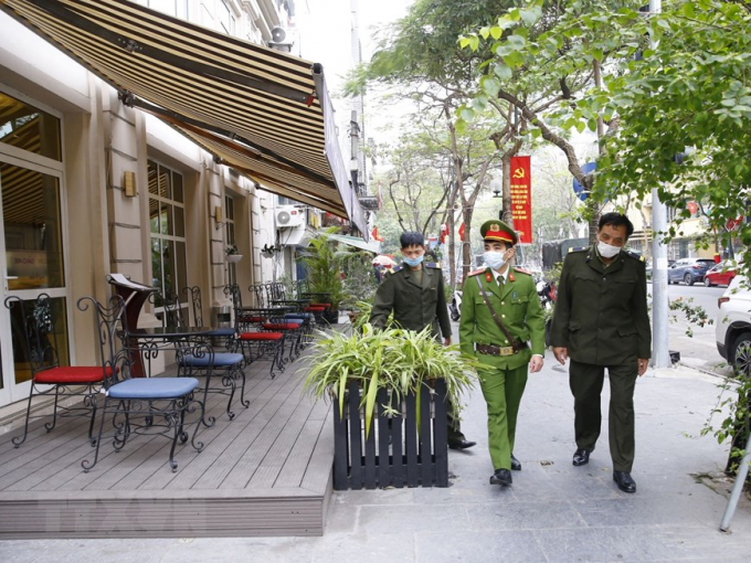 Lực lượng công an phường Cửa Nam ra quân đề nghị các hộ kinh doanh đóng cửa quán ăn đường phố, trà đá, cà phê. Ảnh: Doãn Tuấn/TTXVN