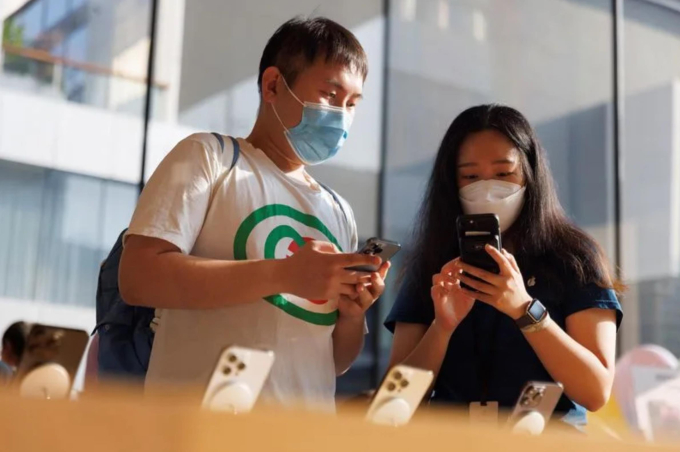    Một khách hàng nói chuyện với nhân viên kinh doanh trong cửa hàng Apple khi các mẫu iPhone 14 của Apple được bán tại Bắc Kinh, Trung Quốc. Ảnh: Reuters  