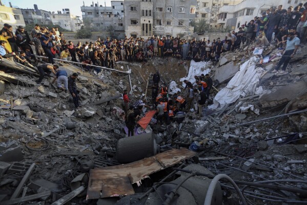 Người dân Palestine tụ tập bên đống đổ nát của một ngôi nhà bị phá hủy sau cuộc không kích của Israel vào thành phố Gaza