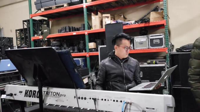 Nhạc trưởng Nhật Minh một tay cầm laptop, một tay đánh đàn cực kỳ chăm chú