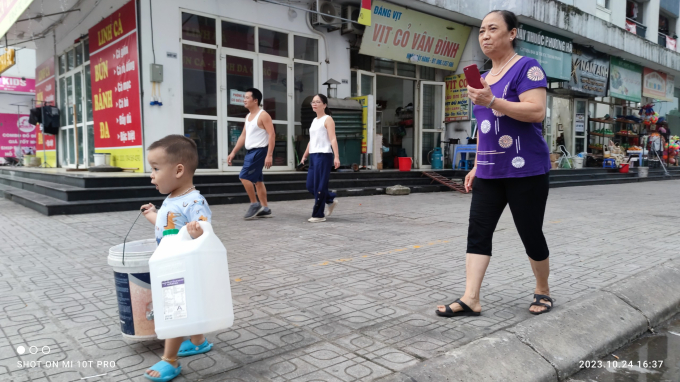 Một em bé theo bà đi xách nước về nhà