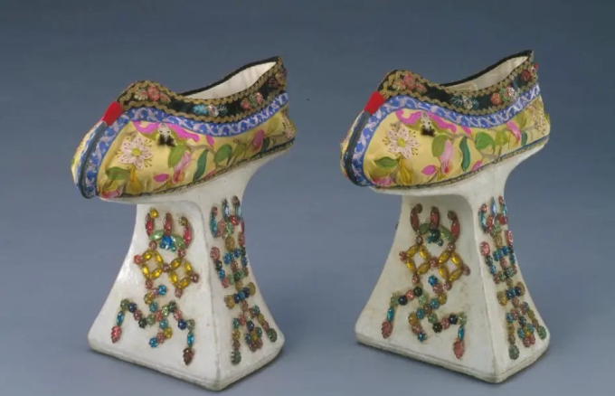 Một đôi giày đế “chậu hoa” từ thời Quảng Tự, phía dưới làm bằng gỗ, bọc vải trắng, sơn bằng bột màu trắng và khảm đá