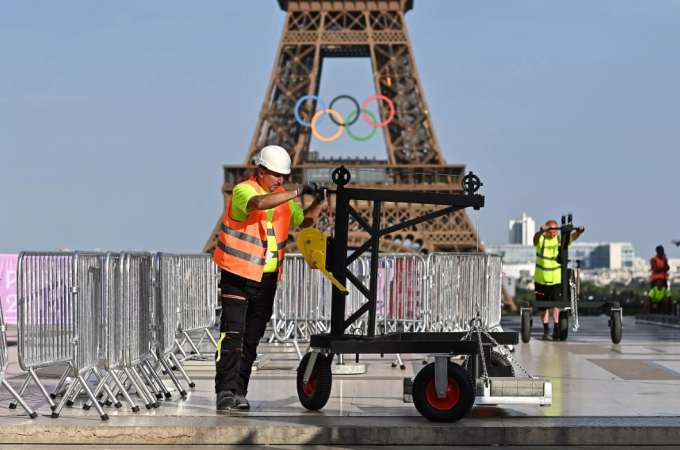 Một nhân viên đang tiến hành dựng rào chắn ở gần chân tháp Eiffel. Ảnh: Manan Vatsyayana/AFP