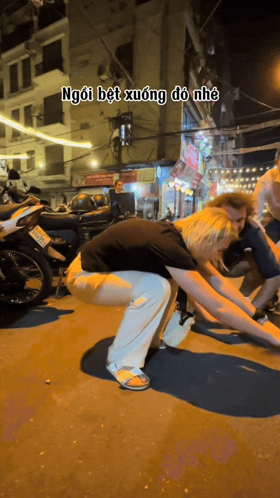 Các vị khách Tây cố gắng giúp đỡ nhau để không bị ngã khi thử ngồi xổm (Ảnh: Phuc Do Tourguide)