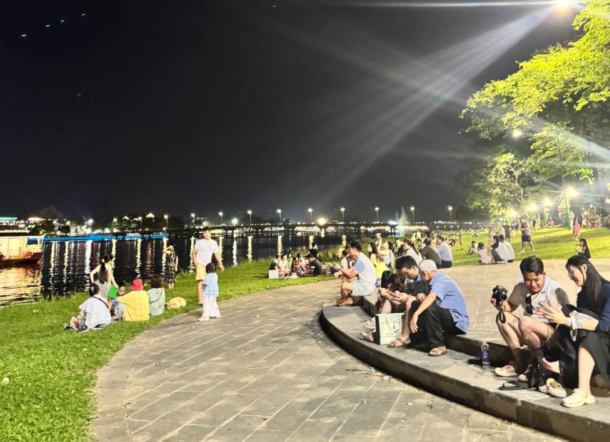 Dù đã 22h nhưng dọc hai bên bờ Sông Hương, từng thảm cỏ vẫn kín chỗ khi người dân và du khách ngồi quây quần, trò chuyện