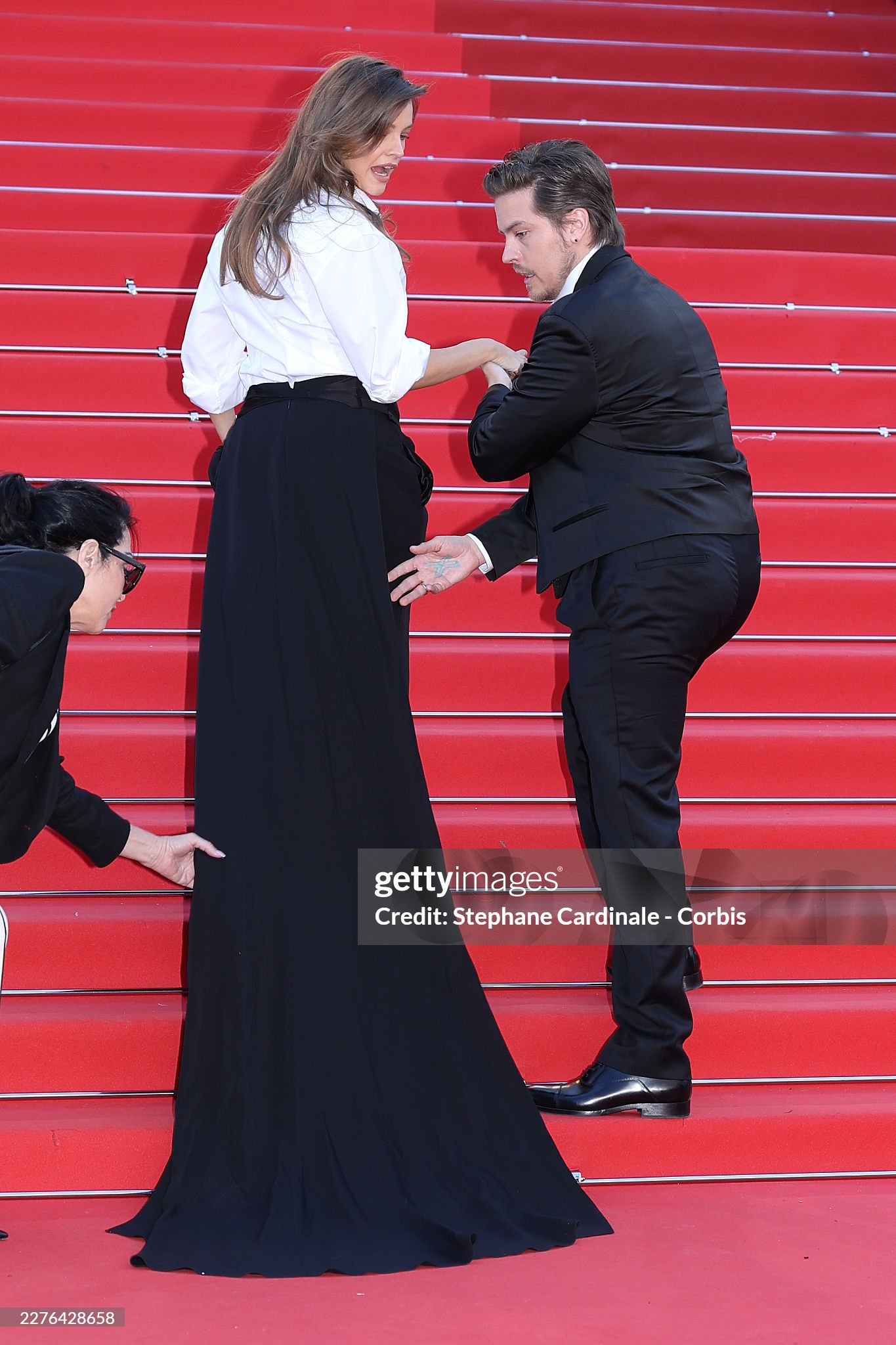 ... rồi đỡ cô bước lên cầu thang. Ảnh: Getty Images