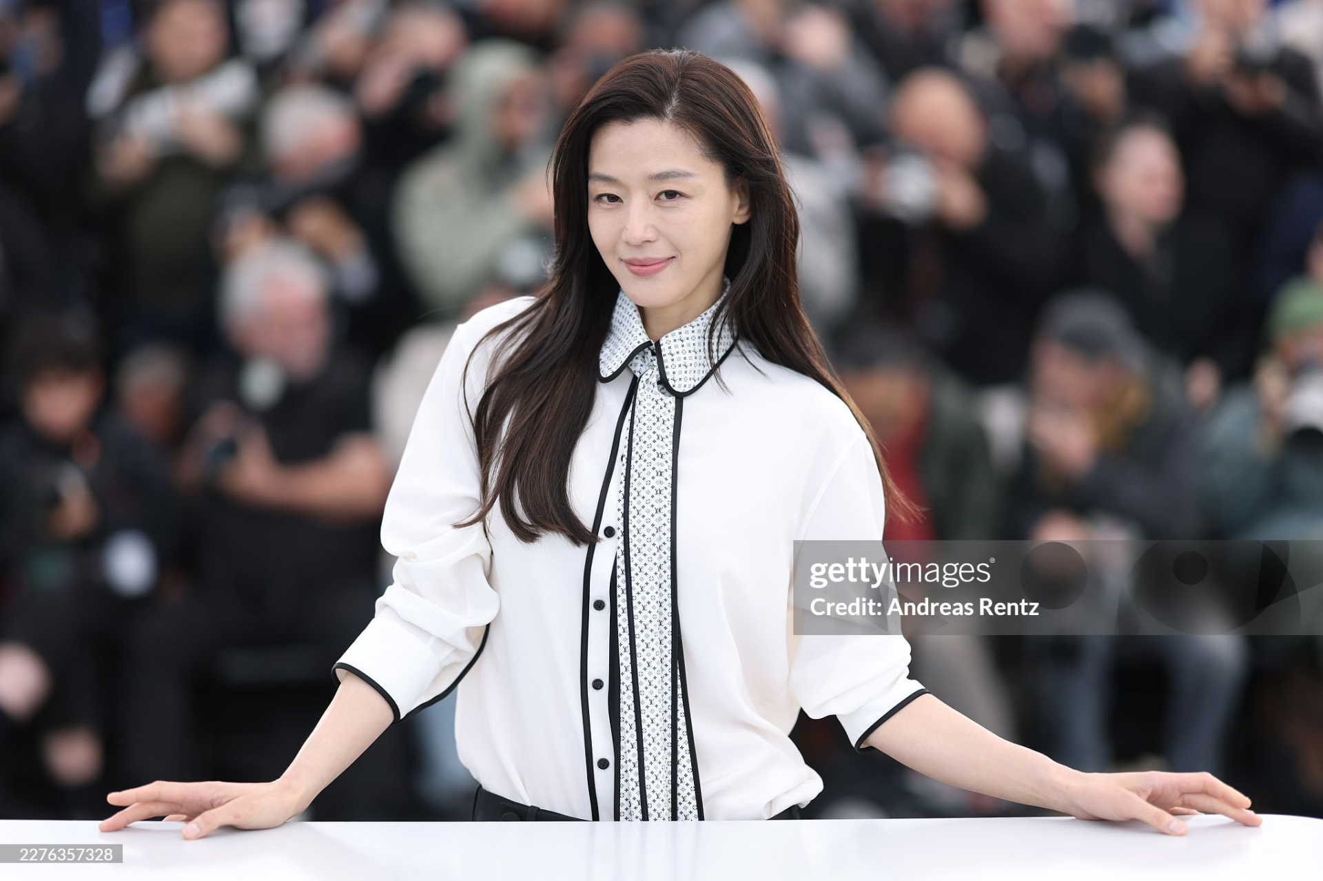   Jeon Ji Hyun có buổi họp báo quảng bá tác phẩm điện ảnh Colony mà mình đóng chính ngoài trời tại LHP Cannes 2026. Cô diện trang phục đơn giản với áo sơmi trắng, quần đen. Kiểu trang điểm tự nhiên, tóc tai rối bời khiến minh tinh xứ Hàn trông nhợt nhạt, kém tươi tắn, không khác gì để mặt mộc và luộm thuộm qua ống kính có độ phân giải cao của 