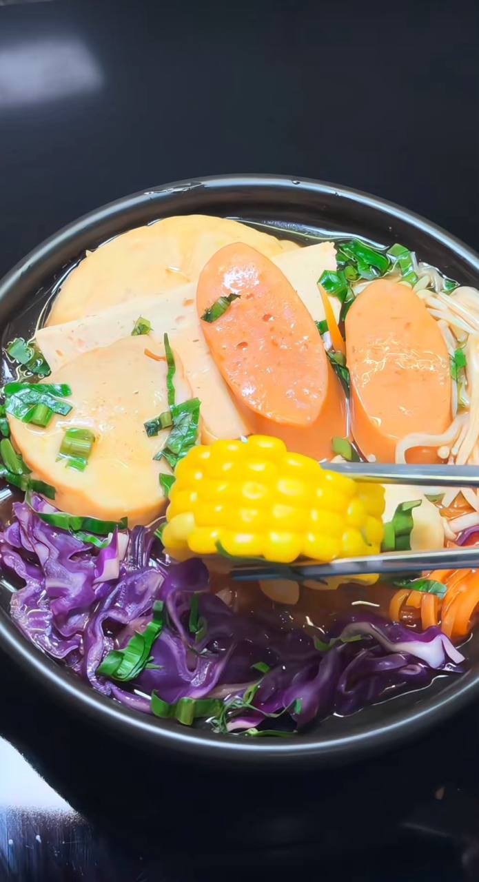 Topping của tô mì có xúc xích chay, viên chả cá chay, nấm kim châm, cà rốt, bắp Mỹ,...