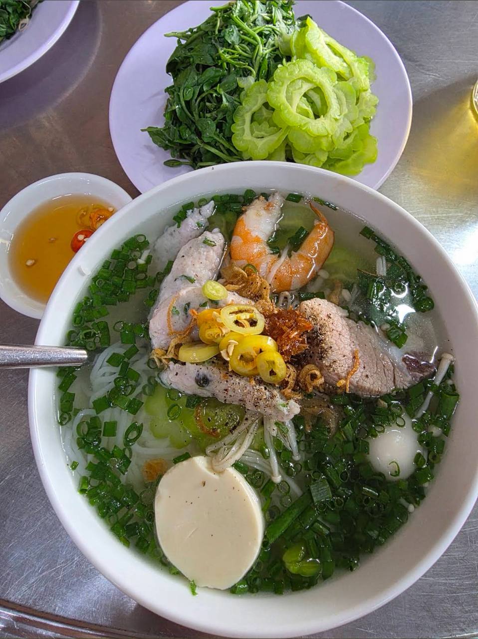 Một tô đầy đủ có cá thác lác, tôm, sườn non, đậu hũ, trứng cút, khổ qua và nấm kim châm. Ảnh: Google Review